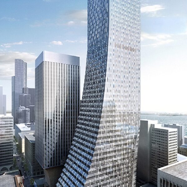 A tall, modern skyscraper with a distinctive curved twist rises above city buildings under a clear sky; its glass facade reflects sunlight and the surrounding urban landscape.