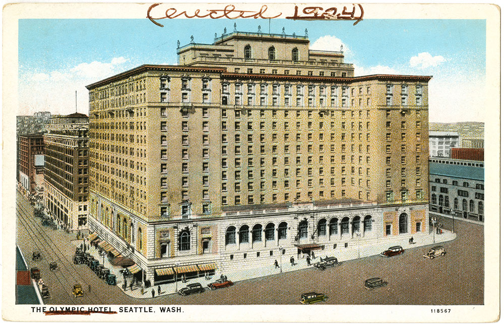 Vintage postcard of The Olympic Hotel in Seattle, Washington, showing a large, grand building with arched windows and cars parked along the streets; “created 1924” is handwritten at the top.